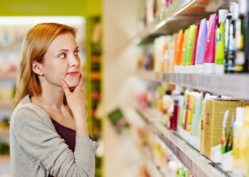 Eine Frau steht vor einem Supermarkt-Regal mit Pflegeprodukten.