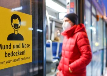 Ein Mann mit Schutzmaske steigt in eine Bahn ein.