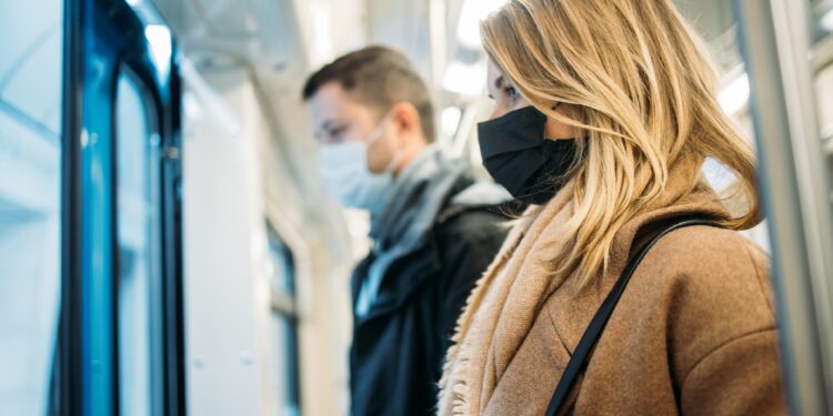 Donna e uomo con protezione bocca e naso in metropolitana
