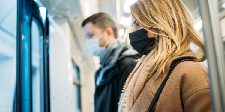 Vrouw en man met mond- en neusbescherming in de metro