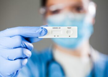 Behandschuhte Hand hält einen Coronavirus-Schnelltest
