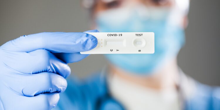 Behandschuhte Hand hält einen Coronavirus-Schnelltest