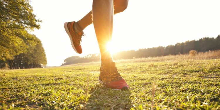 Junger Mann joggt querfeldein auf einer Wiese