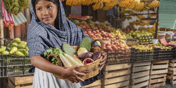 Uma mulher carrega uma cesta de frutas e vegetais.