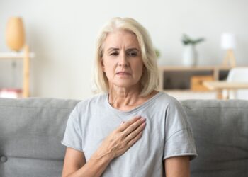 Frau mit Herzschmerzen fasst sich an die Brust
