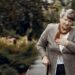 Ältere Frau mit Gehstock fasst sich wegen Atemnot an die Brust