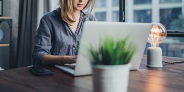 Eine junge Frau arbeitet am Laptop im Homeoffice