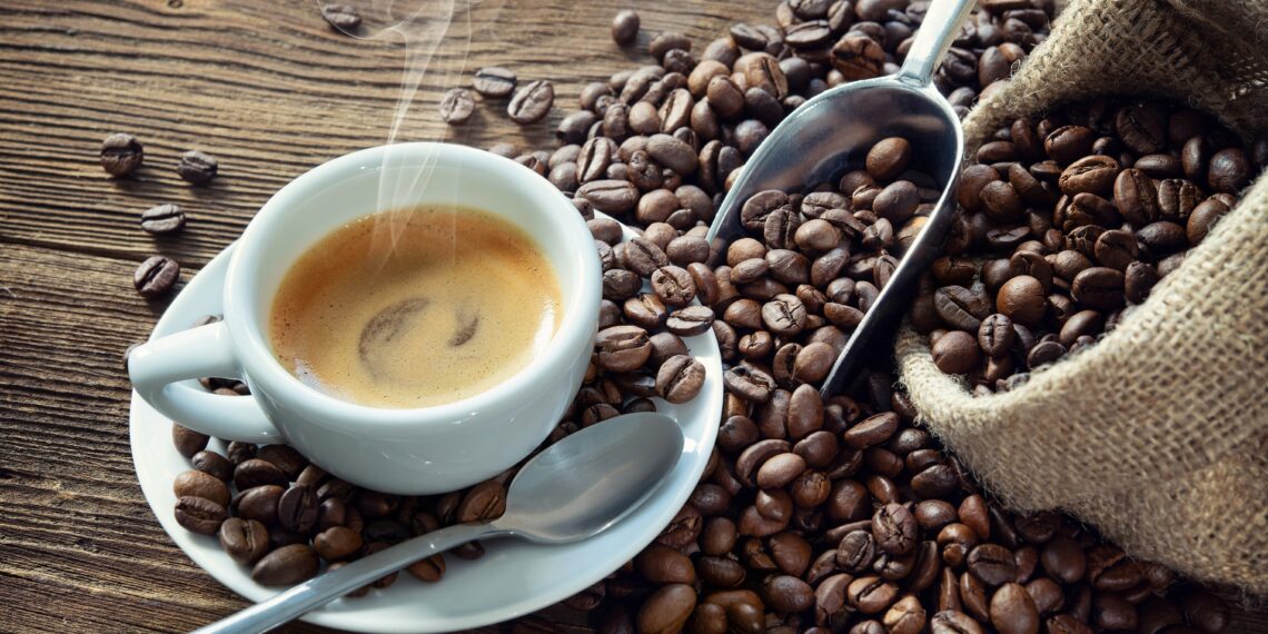 Bild von Kaffee in Tasse zusammen mit Kaffeebohnen.
