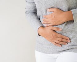 Junge Frau hält sich ihren schmerzenden Bauch