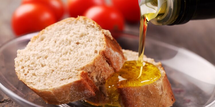 Brotscheiben, auf die Öl gegossen wird, vor frischen Tomaten