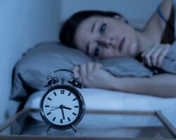 Junge Frau liegt mitten in der Nacht schlaflos im Bett