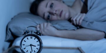 Junge Frau liegt mitten in der Nacht schlaflos im Bett
