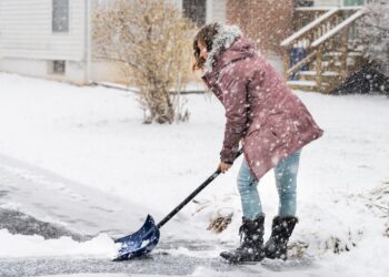 Junge Frau beim Schneeschippen