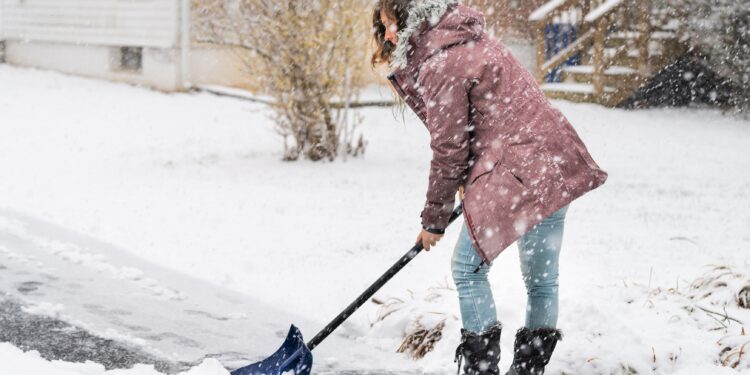 Junge Frau beim Schneeschippen