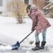 Junge Frau beim Schneeschippen