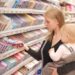 Eine Frau mit einem Baby auf dem Arm nimmt eine Schokolade aus einem Regal im Supermarkt.