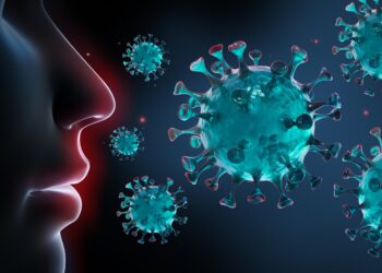 Grafische Darstellung: Coronaviren schweben um Mund und Nase einer Person herum.