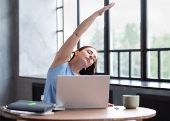 Zu hause am Laptop arbeitende Frau macht Dehnübungen