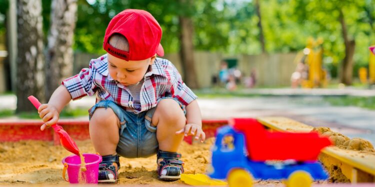 Ein kleiner Junge spielt im Sandkasten.