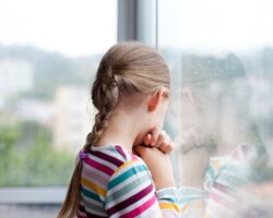 Trauriges Mädchen schaut aus dem Fenster