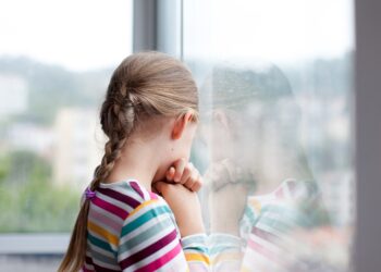 Trauriges Mädchen schaut aus dem Fenster