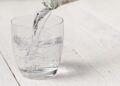 Ein Glas Mineralwasser steht auf einer weißen Oberfläche.