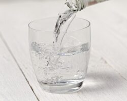 Ein Glas Mineralwasser steht auf einer weißen Oberfläche.