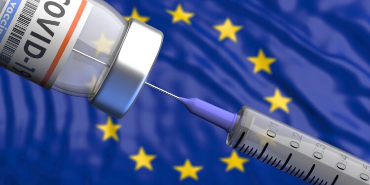 Eine Spritze und eine Dosis COVID-19-Impfstoff vor der europäischen Flagge.