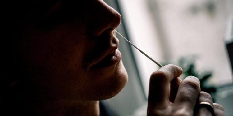 Ein Mann macht einen Nasen-Abstrich mit einem Wattestäbchen.