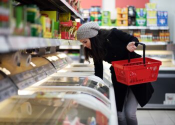 Eine Frau greift in die Tiefkühltruhe in einem Supermarkt.