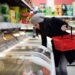 Eine Frau greift in die Tiefkühltruhe in einem Supermarkt.