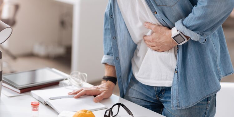 Mann mit Schmerzen hält Hand an seinen Bauch