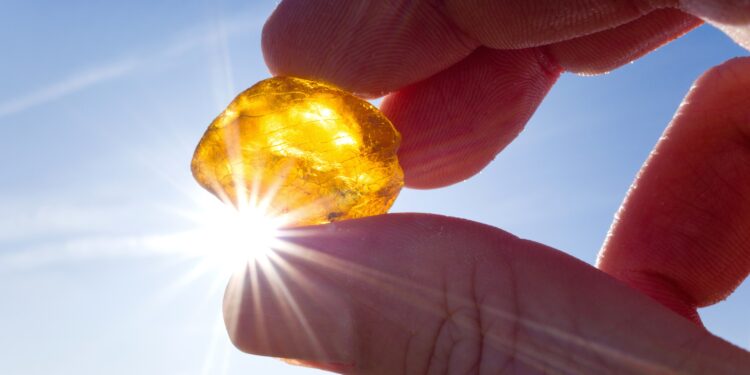 Bernstein zwischen Daumen und Zeigefinger in die Sonne gehalten.