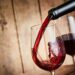 Aus einer Flasche wird Rotwein in ein Weinglas gegossen