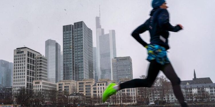 Ein Jogger läuft vor der Skyline von Frankfurt.