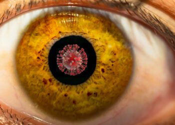 Großaufnahme vom Auge mit Coronaviurs in der Pupille.