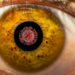 Großaufnahme vom Auge mit Coronaviurs in der Pupille.