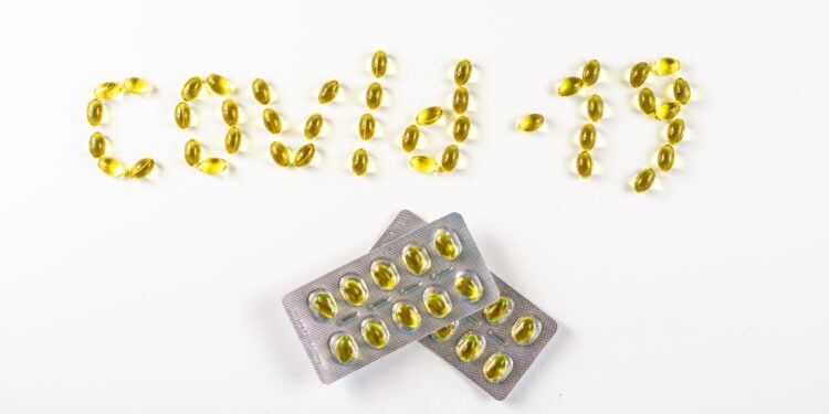 Vitamin D-Pillen wurden so angeordnet, dass sie das Wort "COVID-19" bilden.