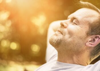 Mann entspannt mit geschlossen Augen in der Sonne.