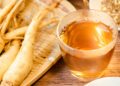 Ginseng-Wurzeln liegen neben einer Glastasse mit Ginsengtee