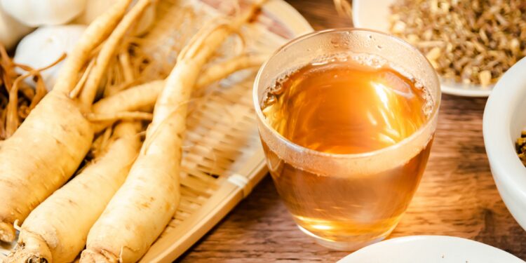 Ginseng-Wurzeln liegen neben einer Glastasse mit Ginsengtee