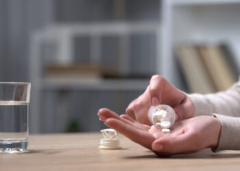 Ältere Frau schüttet Tabletten in ihre Hand