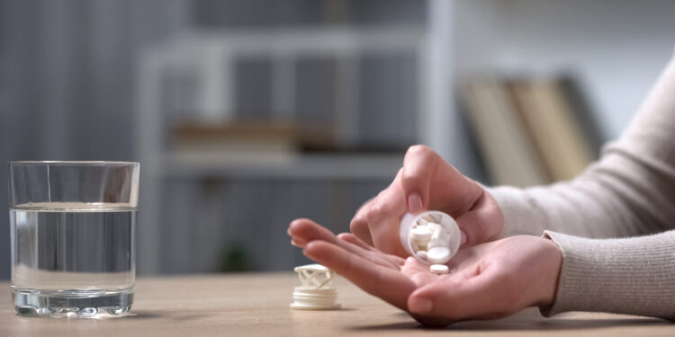 Ältere Frau schüttet Tabletten in ihre Hand