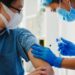 Junge asiatische Krankenschwester impft einen Mann