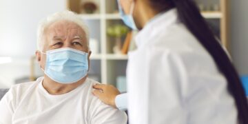 Ärztin und älterer Patient mit Mund-Nasen-Schutz