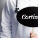 Ein Arzt hält ein Schild mit der Aufschrift "Cortison" hoch.