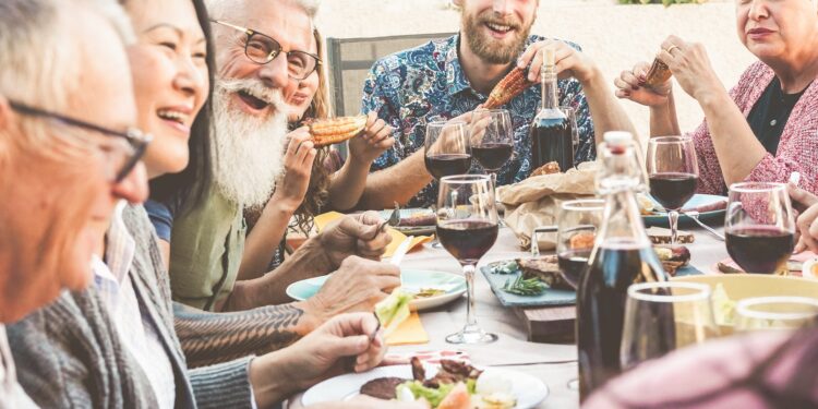 Fröhliche Runde von Menschen beim Essen an einem Tisch im Freien.