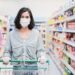 Frau mit Mund-Nasen-Schutz mit Einkaufswagen im Supermarkt