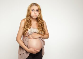 Hochschwangere Frau hält sich den Bauch