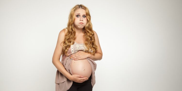 Hochschwangere Frau hält sich den Bauch
